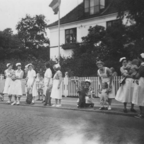 Sort-hvid foto af personale og børn ved vejkant.