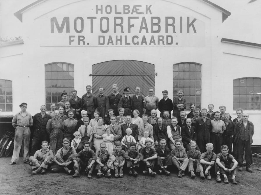 Sort-hvid foto af en gruppe mennesker opstillet foran porten til Holbæk Motorfabrik.