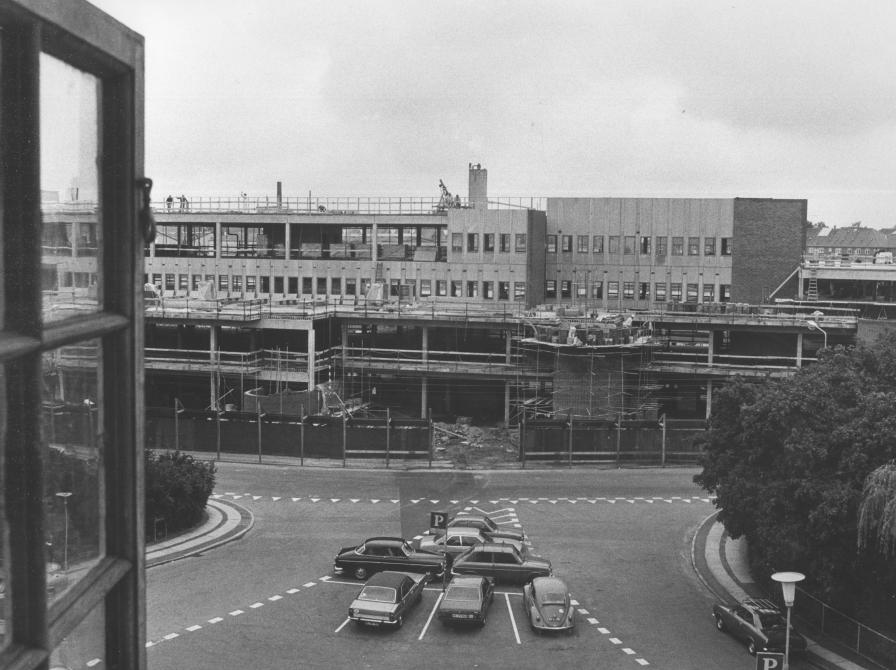 Sort-hvid foto af udsigt fra vindue mod stort byggeri.